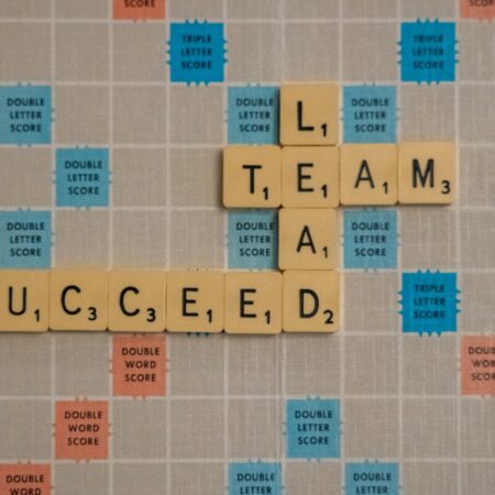 Scrabble board showing words 'Lead', 'Team', and 'Succeed'.